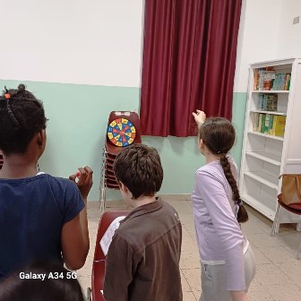 Tre bambini lanciano freccette verso un bersaglio.