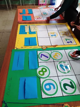 Bambini che dispongono numeri su dei grandi quadrati di cartoncino.