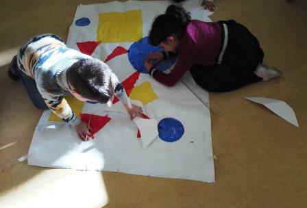 Bambini realizzano un grande quadro con forme geometriche