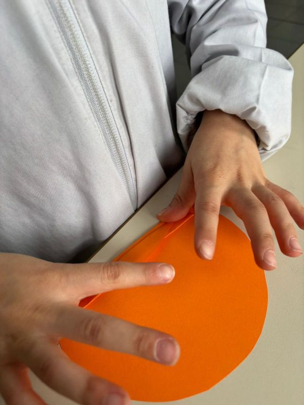 Mani di bambina piegano un cerchio di carta