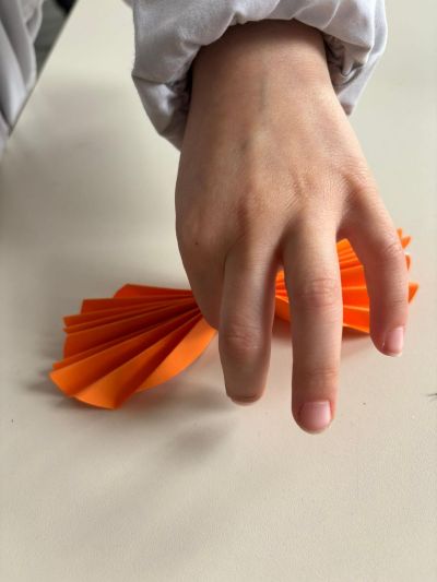 Mano di bambina modella i ventagli di carta, dando loro la forma di ali.