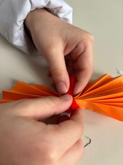 Mani di bambina uniscono due cerchi, piegati a fisarmonica, con un filo colorato.