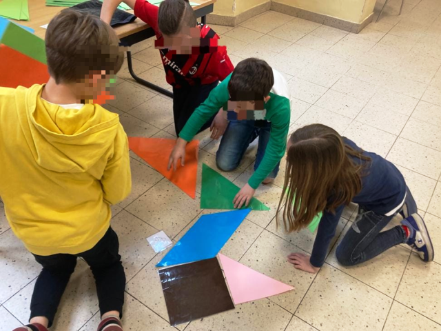 bambini giocano con tessere giganti del Tangram