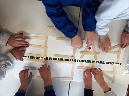Bambini compongono con pezzi di legno la parola "Pace"